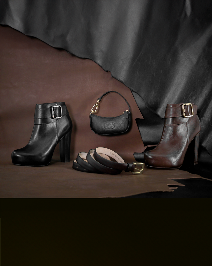 Stylish display of black and brown leather booties with handbags and belts.
