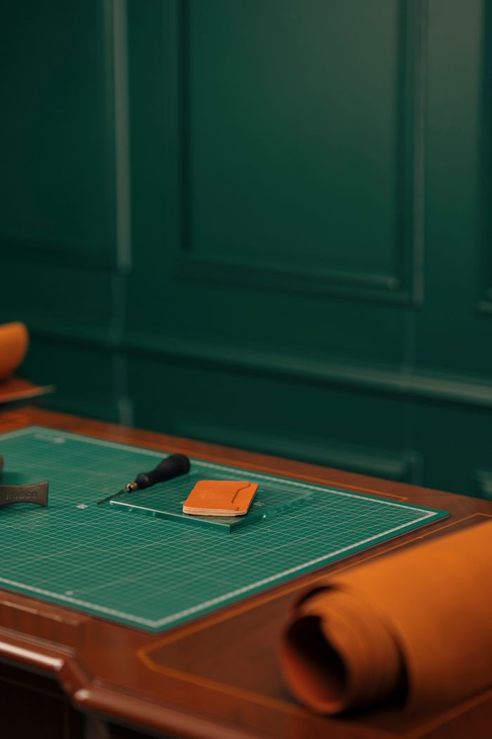Elegant leatherworking table with tools and materials in a sophisticated setting.