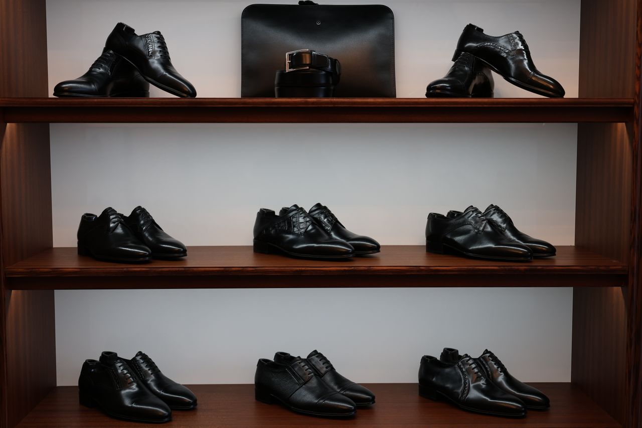 A stylish display of black leather shoes and accessories on wooden shelves in a store.
