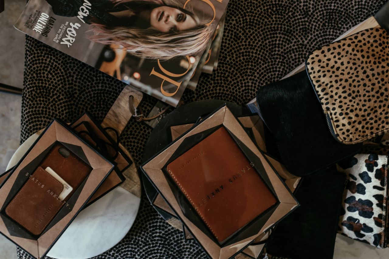 Stylish flat lay of leather accessories and a fashion magazine on a patterned table.